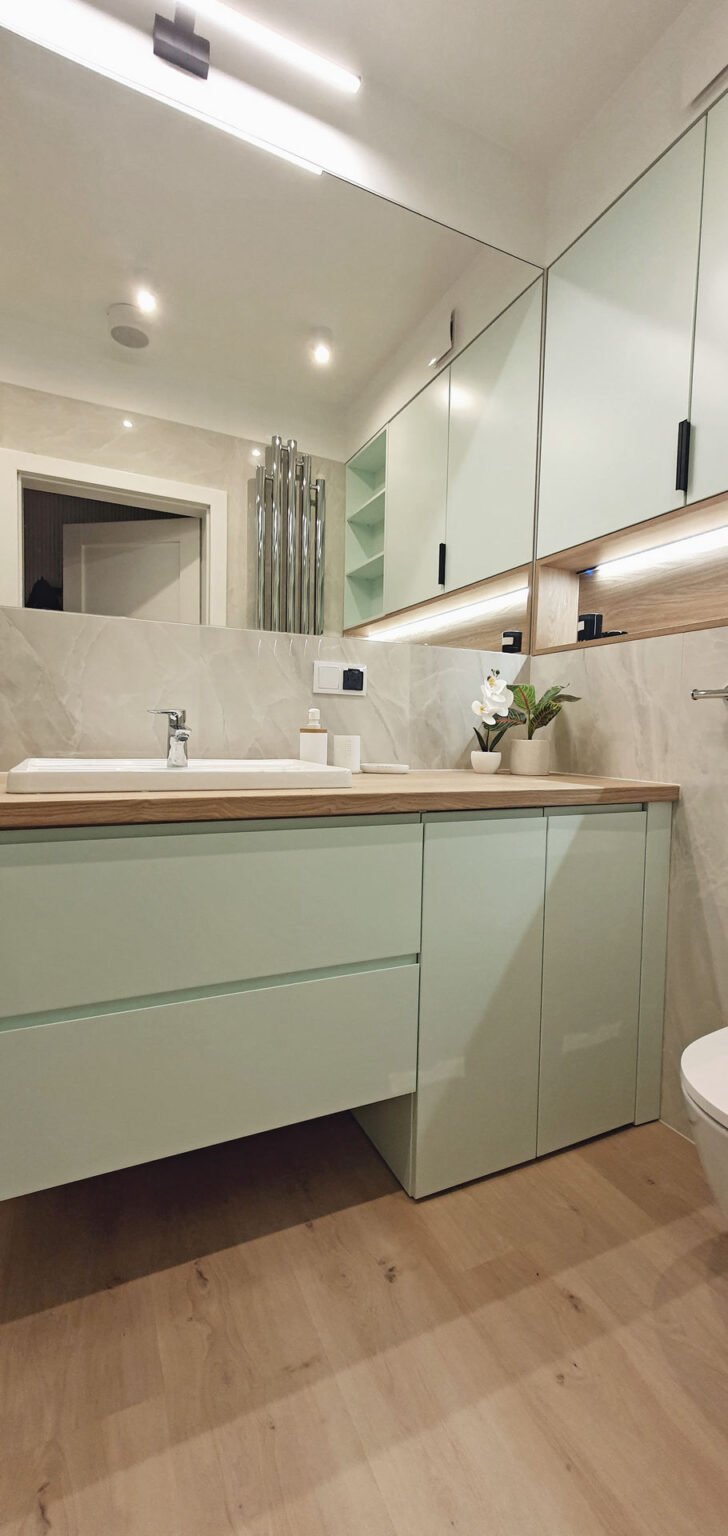 Łazienka z szafkami w kolorze mięty, ukryta pralka pod blatem