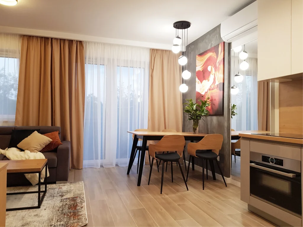 Salon z pomarańczowymi zasłonami, skórzaną sofą i jadalnią w tle – mieszkanie na wynajem przy Przesmyckiego